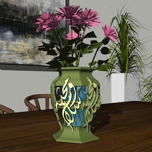 Puede incluir: Un jarrón de cerámica verde con intrincados diseños de caligrafía dorada. El jarrón está lleno de flores rosas y se encuentra sobre una mesa de madera.