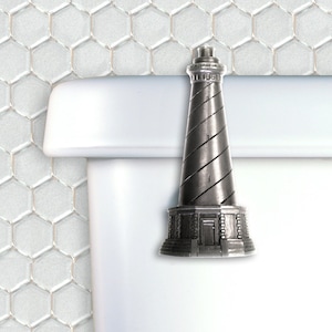 May include: A silver-colored lighthouse-shaped toilet tank lever. The lever is attached to a white toilet tank.