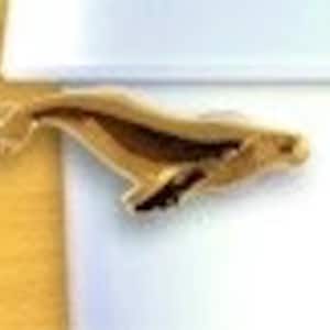 May include: A gold-colored whale pin, a popular charm for jewelry making or as a decorative accent.