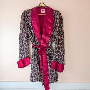 May include: A red and gray patterned robe with a red satin collar and sash. The robe has a label that says "Wembley".