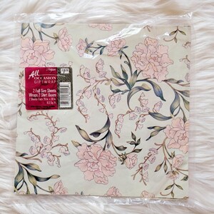 K&ouml;nnte beinhalten: Eine Packung Blumen-Geschenkpapier mit rosa und gr&uuml;nen Blumen auf cremefarbenem Hintergrund. Die Packung tr&auml;gt die Aufschrift "All Occasion Giftwrap" und enth&auml;lt 2 gro&szlig;e Bl&auml;tter, die 2 Hemdenkartons verpacken. Jedes Blatt misst 20 Zoll mal 30 Zoll.