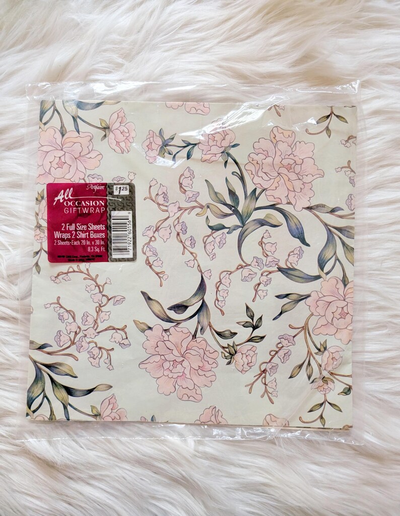 K&ouml;nnte beinhalten: Eine Packung Blumen-Geschenkpapier mit rosa und gr&uuml;nen Blumen auf cremefarbenem Hintergrund. Die Packung tr&auml;gt die Aufschrift "All Occasion Giftwrap" und enth&auml;lt 2 gro&szlig;e Bl&auml;tter, die 2 Hemdenkartons verpacken. Jedes Blatt misst 20 Zoll mal 30 Zoll.