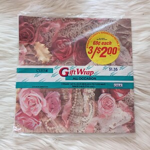 K&ouml;nnte beinhalten: Eine Packung Cleo Geschenkpapier, F&uuml;r Alle Anl&auml;sse, mit einem Blumendesign mit rosa und roten Rosen. Die Packung enth&auml;lt zwei Bogen Geschenkpapier, jeweils 1,67 x 2,5 Fu&szlig; (50,8 cm x 76,2 cm) gro&szlig;. Die Gesamtfl&auml;che betr&auml;gt 8,3 Quadratfu&szlig; (7742 cm&sup2;). Der empfohlene Verkaufspreis betr&auml;gt 1,35 &euro;.