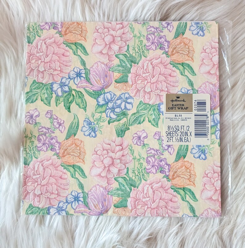 K&ouml;nnte beinhalten: Eine Packung Hallmark Oster Geschenkpapier mit einem Blumenmuster mit rosa, gelben, blauen und gr&uuml;nen Blumen auf einem hellgelben Hintergrund. Die Packung enth&auml;lt zwei Bogen Geschenkpapier, die jeweils 50,8 cm x 60,96 cm gro&szlig; sind. Der Text auf der Packung lautet "Hallmark Easter Gift Wrap $1,55 8 1/3 SQ. FT. (2 SHEETS: 20 IN. X 2FT. 1/2 IN. EA.) 02076".