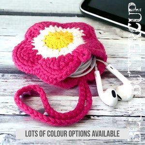 May include: A pink crocheted flower-shaped pouch with a white and yellow centre, holding white earbuds and a cord. The pouch has a pink crocheted strap. "Lots of colour options available" is written below the pouch.