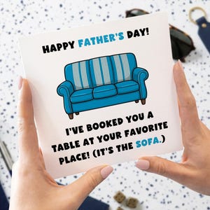 May include: A Father's Day card featuring a blue cartoon sofa and the text "HAPPY FATHER'S DAY!". The card also states "I'VE BOOKED YOU A TABLE AT YOUR FAVORITE PLACE! (IT'S THE SOFA.)".