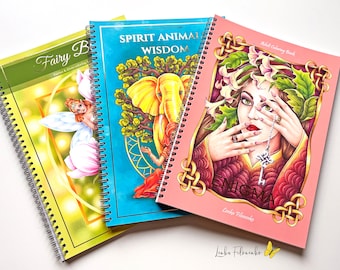 May include: Three spiral bound coloring books with colorful covers. The first book is green and yellow with the text "Fairy Book" on the cover. The second book is blue with the text "Spirit Animal Wisdom" on the cover. The third book is pink with the text "Enigma" on the cover.