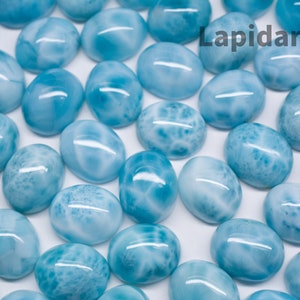 May include: A collection of oval-shaped, light blue and white gemstone cabochons. The stones have a swirling, marbled pattern.