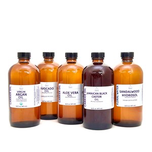 May include: Five amber glass bottles with white labels containing various carrier oils and hydrosols. The labels list the product names, such as Virgin Argan Oil, Avocado Oil, Aloe Vera Oil, Jamaican Black Castor Oil, and Sandalwood Hydrosol. Each bottle is 16 fl oz (473 ml).