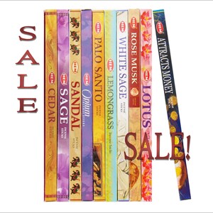 May include: A variety pack of HEM incense sticks in various scents, including Cedar, Sage, Sandal, Opium, Palo Santo, Lemongrass, White Sage, Rose Musk, Lotus, and Attracts Money. The sticks are arranged vertically in a row, with the brand name HEM visible on each box. The text "SALE!" is written in red letters across the image.