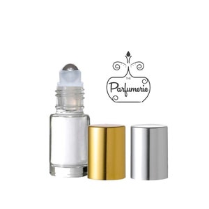 May include: A clear glass roller bottle with a silver roller ball and a gold cap. The bottle is sitting on a white background. The bottle is labeled "The Parfumerie".