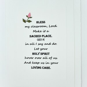 May include: A white card with a pink flower and black text that reads: "BLESS my classroom, Lord. Make it a SACRED PLACE. GUIDE ME in all I say and do. Let your HOLY SPIRIT hover over all of us. And keep us in your LOVING CARE."