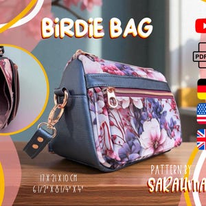Könnte beinhalten: Birdie Bag mit floralem Muster, Maße 17 x 21 x 10 cm. Die Tasche hat einen Reißverschluss, goldfarbene Hardware und einen abnehmbaren Riemen. Der Text "BIRDIE BAG" wird oben angezeigt. Das Muster ist von SarahMariam.