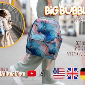 May include: A Big Bubble backpack with a vibrant abstract pattern in blue, pink, and gold. It features a front pocket and side pockets. The dimensions are 42 cm x 32 cm (17" x 12 1/2").