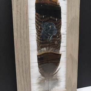 May include: A framed painting of a black dog on a feather. The feather is brown and white with a black background. The dog is looking to the right. The painting is signed "CH 2014".