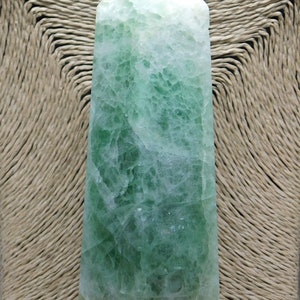 May include: A green fluorite crystal point with a white and green color pattern. The crystal is polished and has a smooth surface.