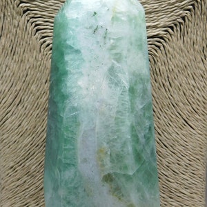 May include: A green fluorite crystal point with a white and green color pattern. The crystal is polished and has a smooth surface.