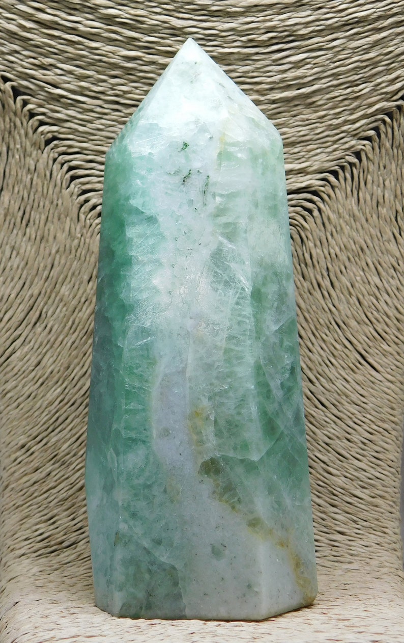 May include: A green fluorite crystal point with a white and green color pattern. The crystal is polished and has a smooth surface.