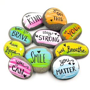 May include: Painted rocks with inspirational messages, including "be kind", "be brave", "stay strong", "you got this", "you can", "smile", "just breathe", "you matter", "have hope", and "be you".