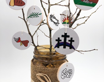May include: A white branch with nine round white ornaments hanging from it. Each ornament has a different black and white illustration depicting a scene from the Easter story. The branch is in a brown glass jar with a burlap covering and a brown ribbon.