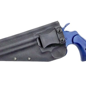 Könnte beinhalten: Ein schwarzes Lederholster mit einem Gürtelclip und einem blauen Revolver.