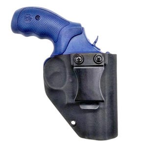 May include: A blue revolver with a textured grip is partially encased in a black moulded holster. The holster features a black metal belt clip secured by two screws and a single circular eyelet at the bottom edge, providing a secure fit.
