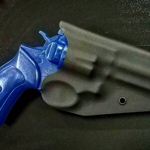 May include: A blue revolver handgun in a black leather holster. The holster has a single snap closure and a small hole on the side.
