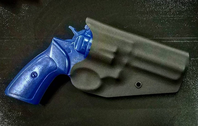 May include: A blue revolver handgun in a black leather holster. The holster has a single snap closure and a small hole on the side.
