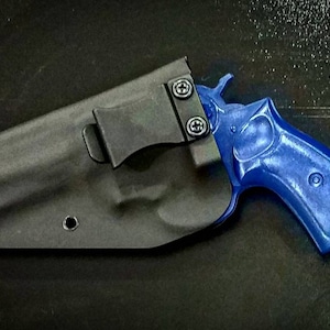 May include: A black leather holster with a clip for a blue handgun. The holster has a single hole on the side.