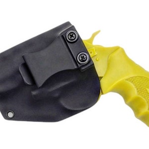 Könnte beinhalten: Eine schwarze Holster mit einer gelben Handfeuerwaffe. Die Holster besteht aus einem strapazierfähigen Material und verfügt über einen Gürtelclip. Die Handfeuerwaffe hat einen gelben Griff und ist teilweise in der Holster sichtbar.