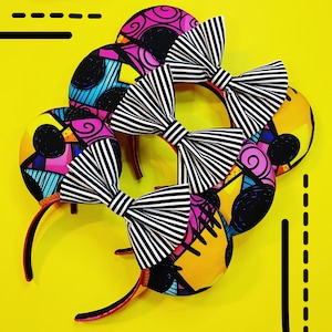 May include: A collection of headbands with black and white striped bows and colorful, patterned ear details. The headbands have a bright yellow background with black graphic lines.