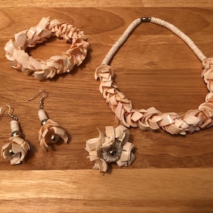 May include: A set of shell jewelry including a necklace, bracelet, and earrings. The jewelry is made of white and pink shell pieces and features silver accents.