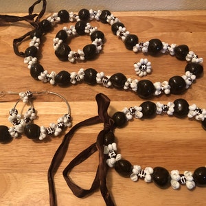 May include: A set of brown and white seed bead jewelry, including a long necklace, a shorter necklace, a bracelet, a pair of hoop earrings, and a small flower-shaped brooch.