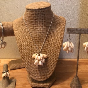 May include: A set of jewelry featuring a necklace, earrings, bracelet, and ring. Each piece is made with a cluster of small white seashells.