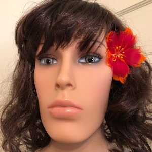 May include: A red and orange feather flower hair clip. The flower is approximately 5 cm in diameter and has a gold centre.