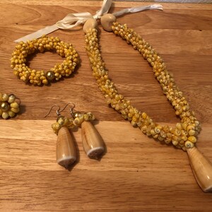 May include: A set of yellow shell jewellery, comprising a necklace, bracelet, earrings, and a ring. The necklace and bracelet are made from small, yellow shells, while the earrings and ring feature larger, more prominent shells.