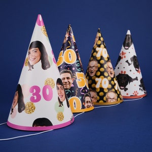 May include: Four party hats with different designs. The first hat has a white background with a pink 30, gold glitter, and a woman's face. The second hat has a black background with a yellow 50, a man's face, and confetti. The third hat has a black background with a yellow 70, a man's face, and white polka dots. The fourth hat has a white background with a black dog's face, paw prints, and bones.