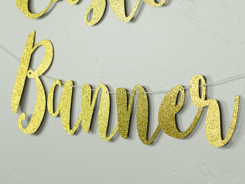 May include: Gold glitter banner with the word "Banner" in cursive lettering.