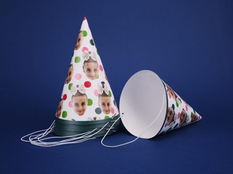 Peut inclure: Deux chapeaux de f&ecirc;te blancs avec une bordure verte. Un chapeau a un fond blanc avec des pois verts, roses et rouges et plusieurs images du visage d'une personne. L'autre chapeau est blanc uni.