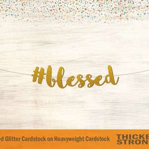 May include: Gold glitter cardstock banner with the text "#blessed" on a white wood background. The banner is made of non-shed glitter cardstock on heavyweight cardstock.