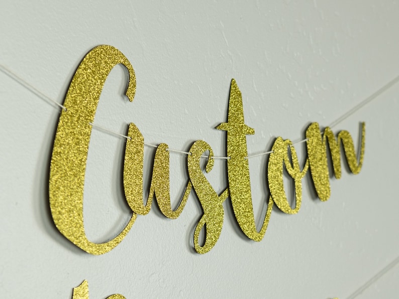 May include: Gold glitter custom banner with the word "Custom" in cursive lettering.