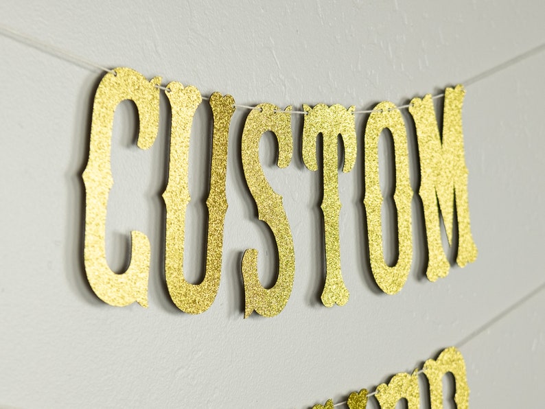 May include: Gold glitter banner with the word "CUSTOM" in a decorative font.