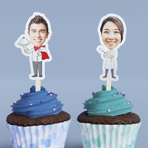 May include: Two cupcakes with blue and green frosting, topped with personalized chef toppers. The chef toppers feature photos of people's faces.