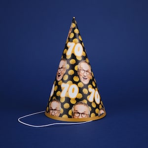 Peut inclure: Un chapeau de f&ecirc;te noir et or avec une ficelle blanche. Le chapeau est d&eacute;cor&eacute; d'un motif de points jaunes et du nombre "70" r&eacute;p&eacute;t&eacute; plusieurs fois. Il y a aussi des images de visage de personne sur le chapeau.