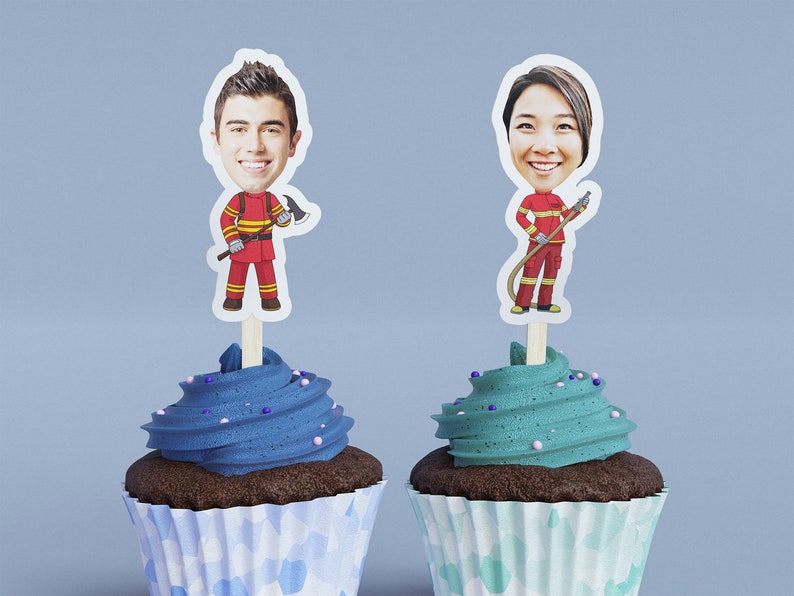 May include: Two cupcakes with blue and green frosting and sprinkles. Each cupcake has a topper with a cartoon image of a person dressed as a firefighter.