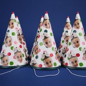 Peut inclure: Cinq chapeaux de f&ecirc;te blancs &agrave; pois verts et rouges avec des visages diff&eacute;rents imprim&eacute;s dessus. Les chapeaux ont des liens en ficelle verts et blancs.