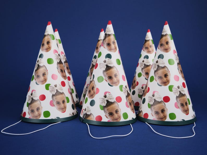 Peut inclure: Cinq chapeaux de f&ecirc;te blancs &agrave; pois verts et rouges avec des visages diff&eacute;rents imprim&eacute;s dessus. Les chapeaux ont des liens en ficelle verts et blancs.