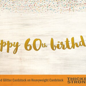 May include: Gold glitter banner with the text "happy 60th birthday". The banner is made of non-shed glitter cardstock on heavyweight cardstock. The text "THICKER & STRONGER" is printed in black at the bottom of the image.