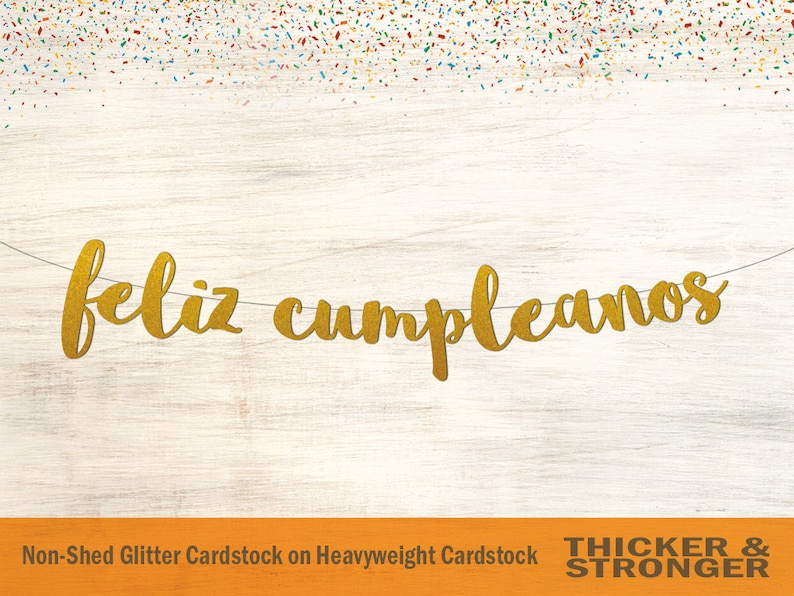 Peut inclure: Banni&egrave;re dor&eacute;e &agrave; paillettes "Feliz Cumplea&ntilde;os" sur un fond en bois blanc. La banni&egrave;re est faite de papier cartonn&eacute; paillet&eacute; non-effiloch&eacute; sur papier cartonn&eacute; &eacute;pais.