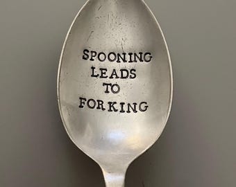 May include: A silver spoon with the text "SPOONING LEADS TO FORKING" engraved on the front.